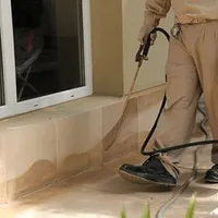 General pest control technician spraying exterior perimeter around a home in Manchester, NH